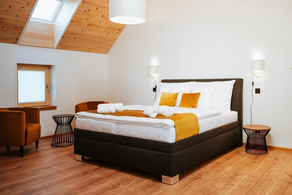 Een moderne slaapkamer met een groot bed, twee nachtkastjes, een bureau en een stoel.