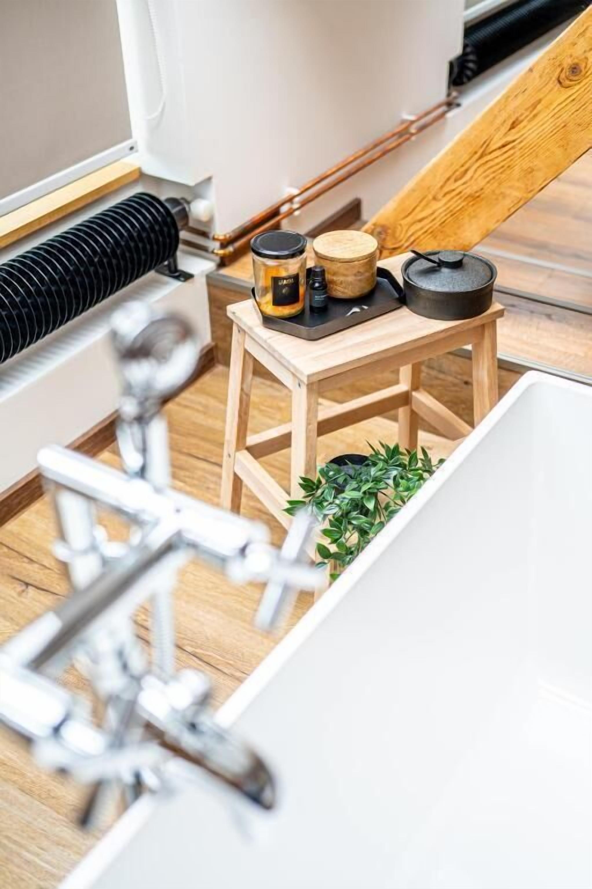 Un baño pequeño y funcional con un taburete de madera, una planta y un lavabo.