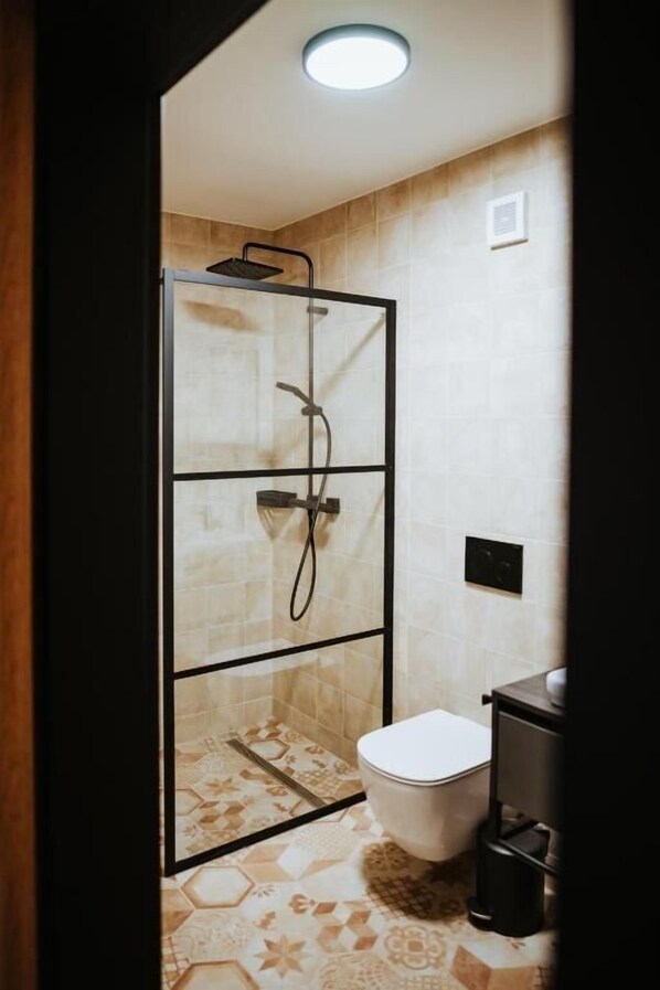 Un baño con cabina de ducha, inodoro y lavamanos.
