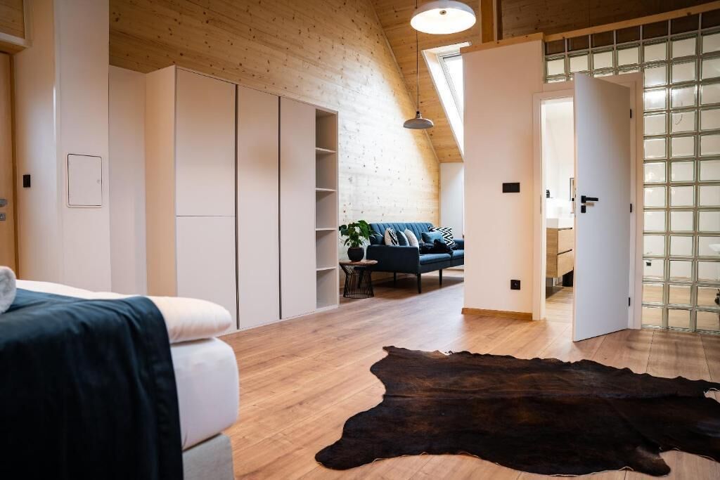 A modern interior with a wooden ceiling, a large window, and a sofa in the background.