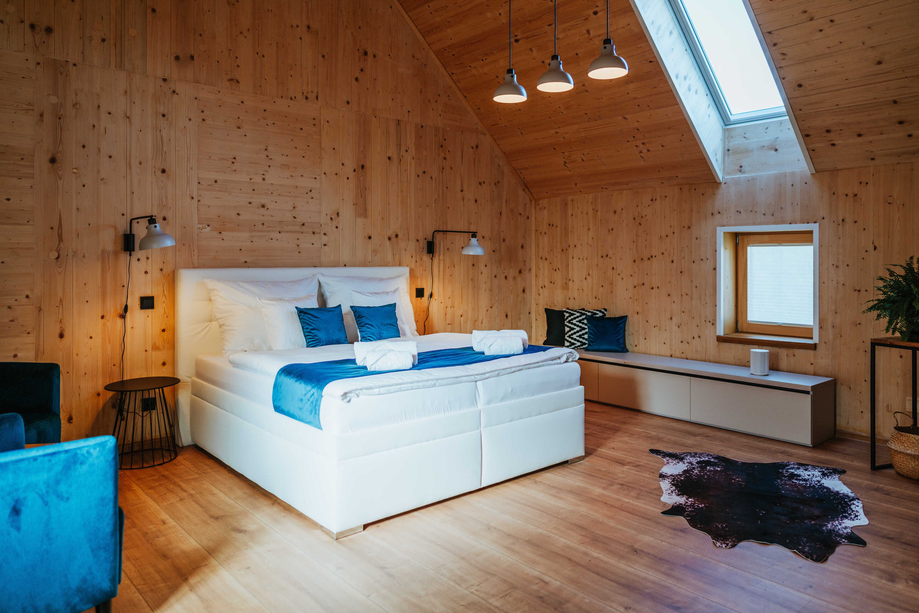 Un dormitorio moderno con una cama grande, un banco y un tragaluz.