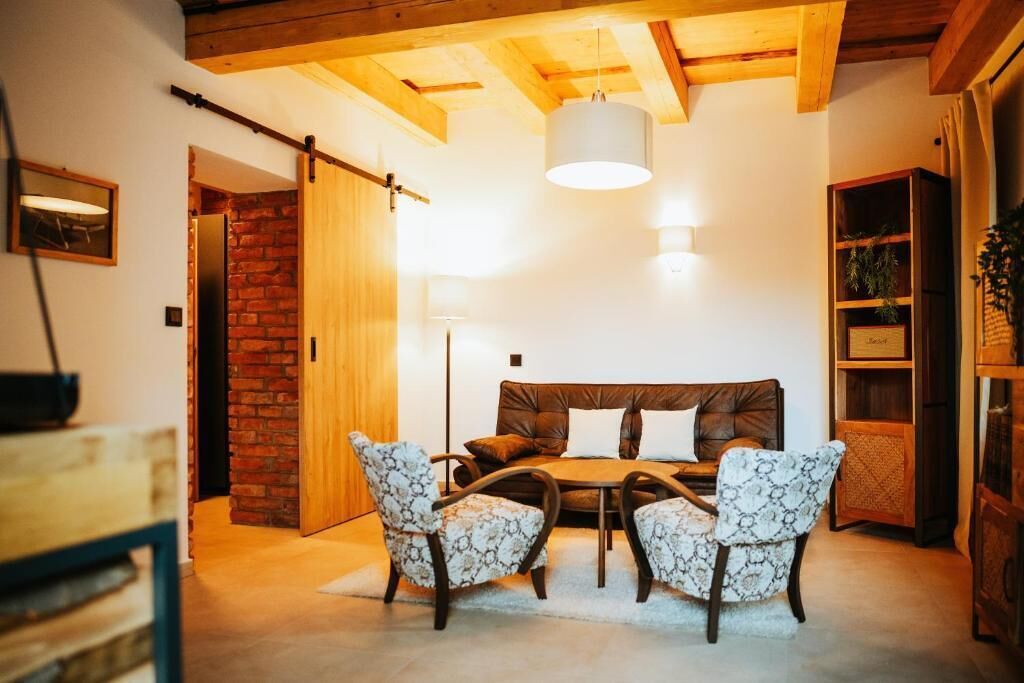 A cozy living room with a leather sofa, patterned chairs, a wooden coffee table, and a hanging light fixture.