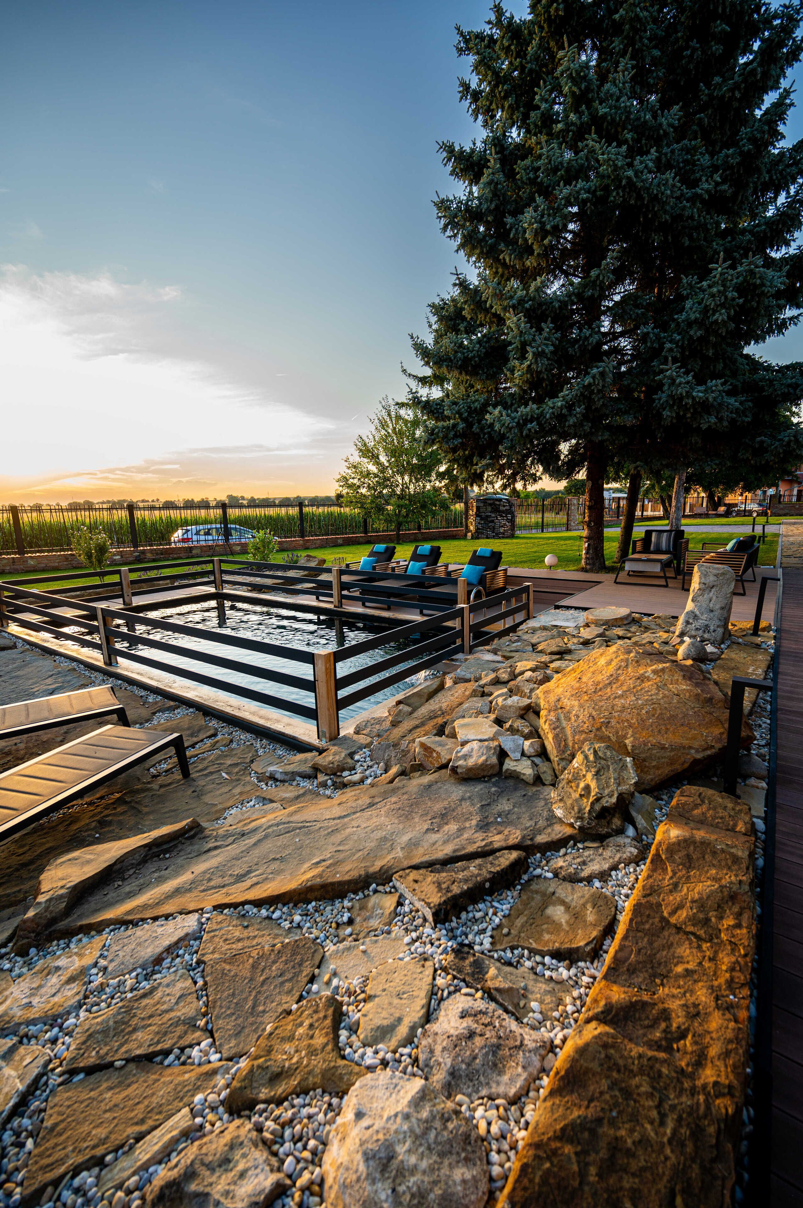 An outdoor patio area with a pool, lounge chairs, and a stone pathway.