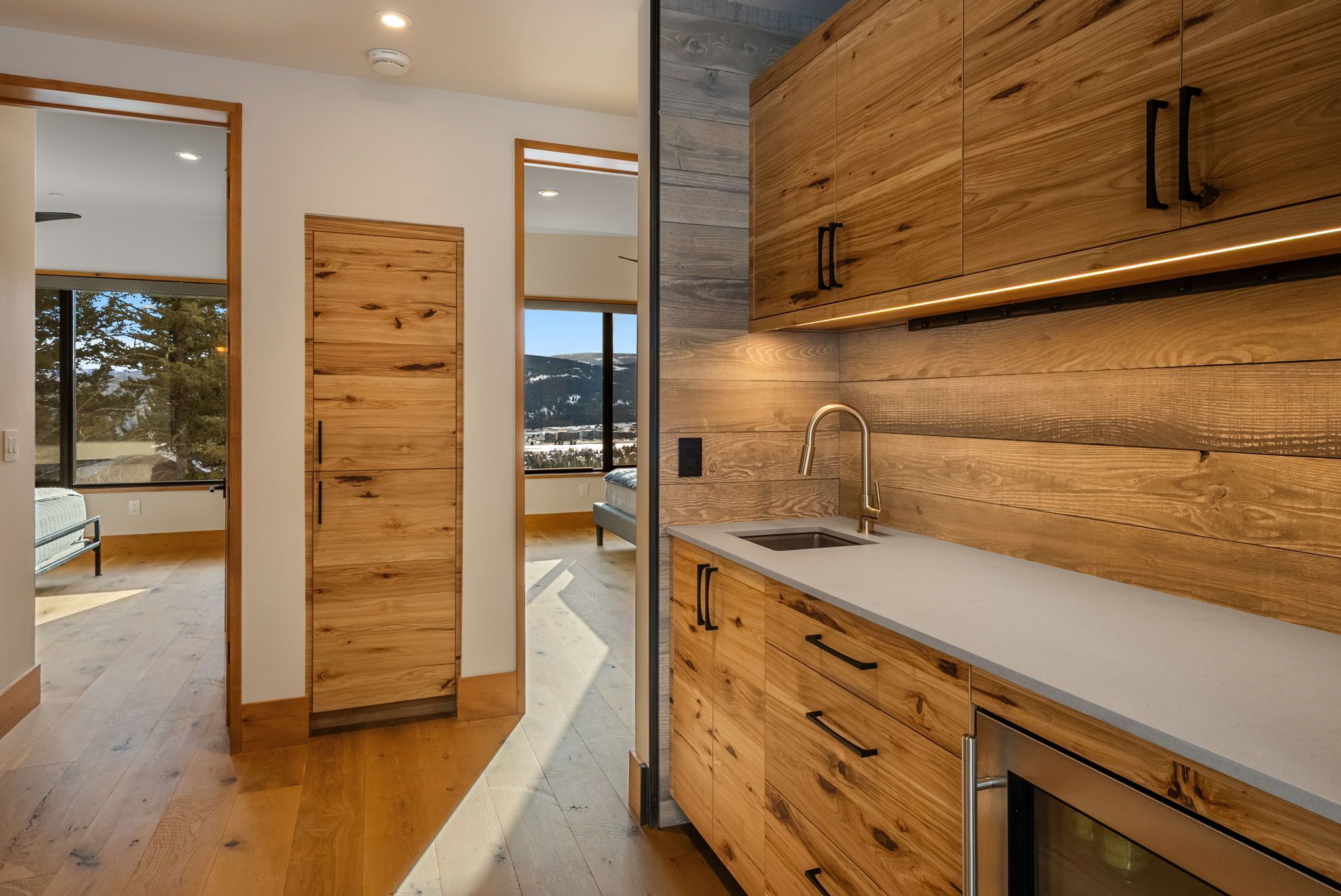 Your modern kitchen features warm wood cabinetry, sleek countertops, and mountain views through expansive windows.