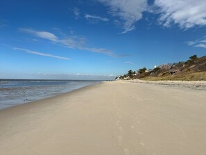 A beach with a clear sky, a sandy shore, and houses on a hillside. - Waterfront Private Beach byCountry Road Properties (Lower Township)