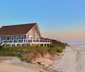 A beachfront house with a balcony, a sandy beach in the background, and a clear sky. - Waterfront Private Beach byCountry Road Properties (Lower Township)