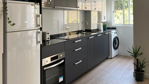 A modern kitchen with a built-in oven, microwave, and dishwasher. There is a window providing natural light and a view of the outdoors. - Malaga Apartment, 300 meters from the sea (Málaga)