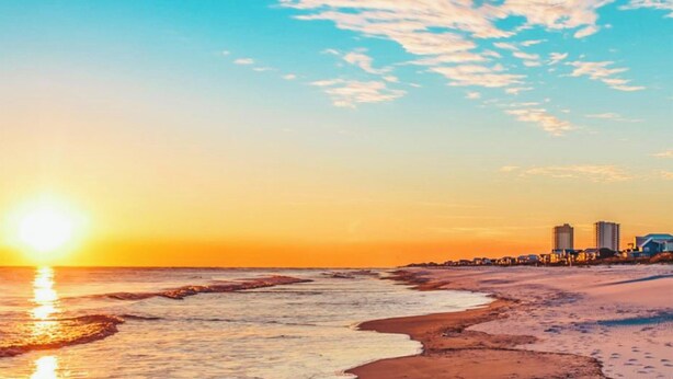 A beach with a sunset, sandy shore, and buildings in the background. - Family-Friendly Retreat Near Gulf Shores, Beach (Foley)