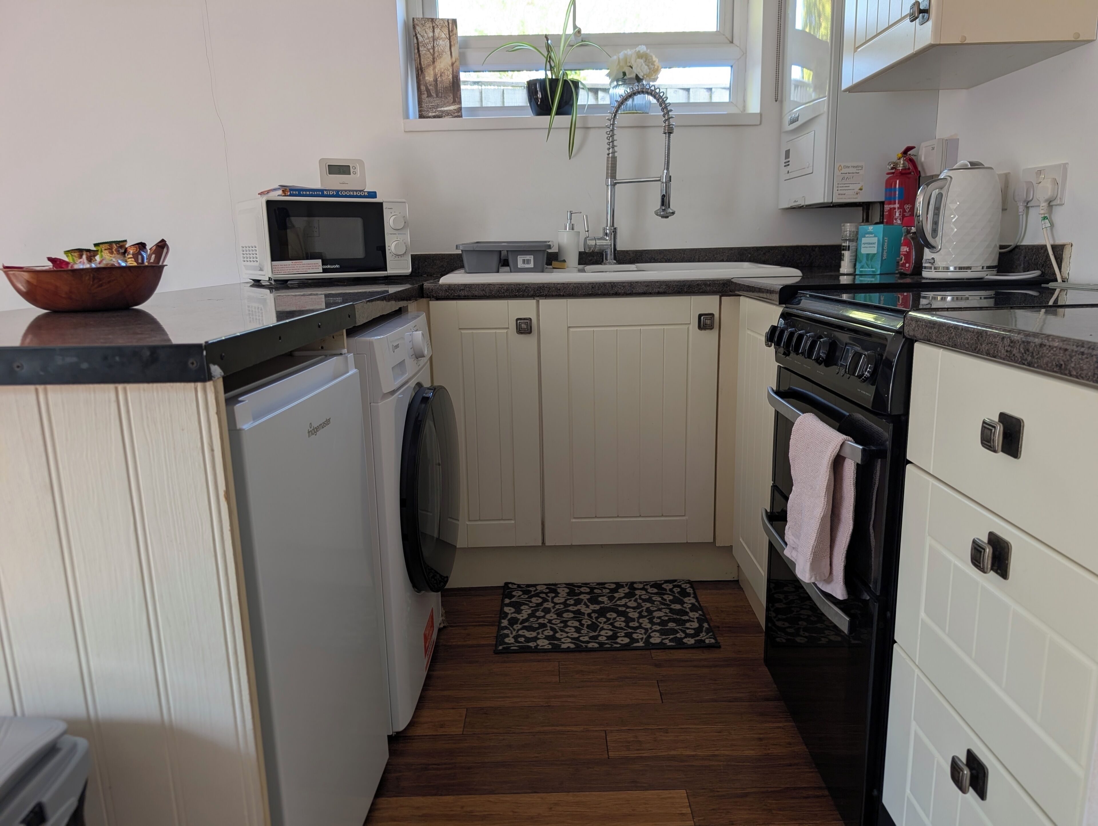 A compact kitchen with a microwave, sink, stove, and dishwasher.