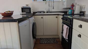 A compact kitchen with a microwave, sink, stove, and dishwasher.