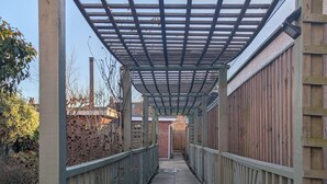 A covered walkway with a metal roof, flanked by wooden fences and a brick wall in the background. - Self-Contained Flat in Didcot near Shops, Milton Park, Harwell & Station (Didcot)