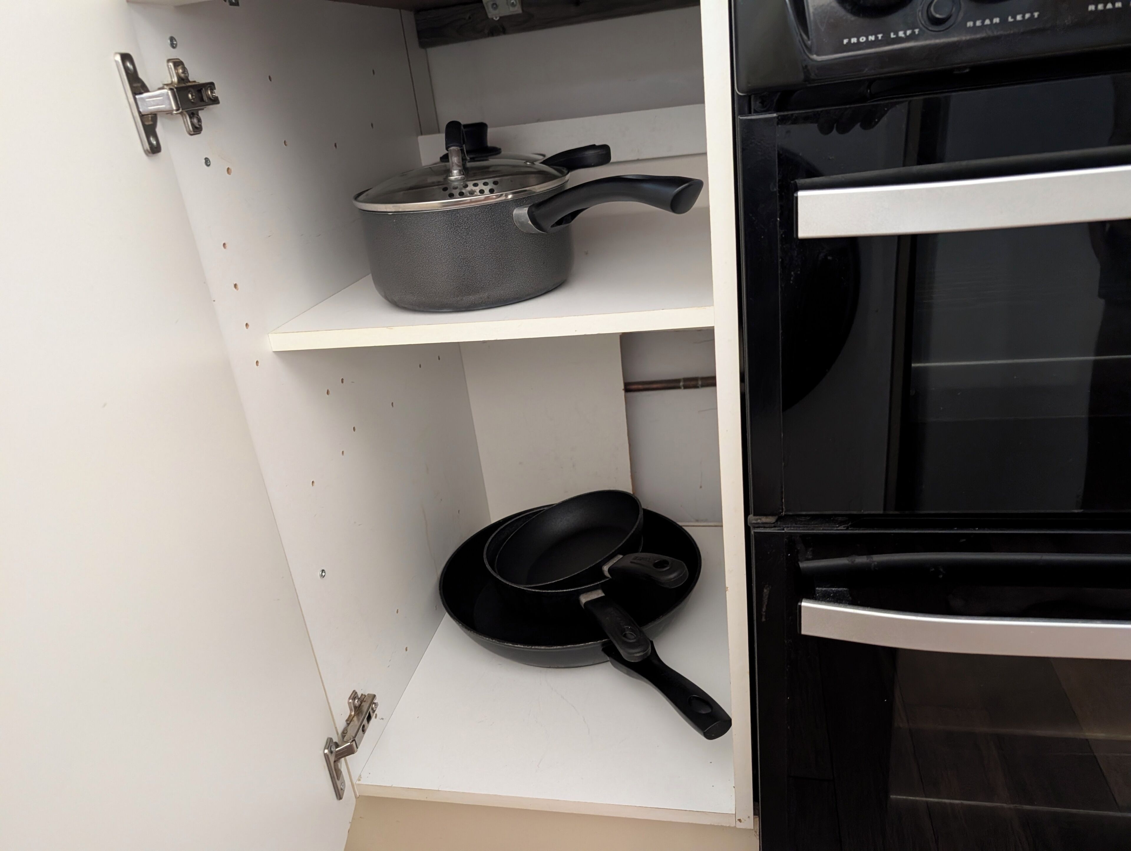 Une cuisine équipée d’une cuisinière, d’un four et d’une casserole posée sur l’étagère supérieure.