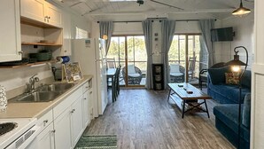Eine geräumige Küche mit Holzausstattung, ein Essbereich mit Tisch und Stühlen sowie ein gemütliches Wohnzimmer mit einer Couch und einem Fernseher.