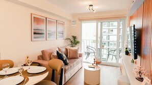 Un salon moderne avec un canapé, une table à manger et des chaises. Il y a un balcon avec vue sur la ville.