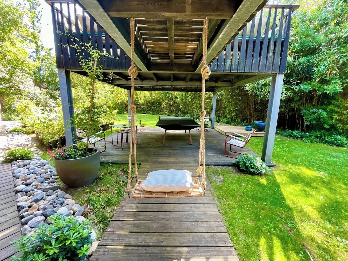 A wooden deck with a swing set, a covered seating area, and a garden path.