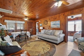 A wooden interior with a dining area, a sofa, and a patterned rug.