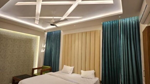 Une chambre à coucher moderne avec un grand lit, un ventilateur de plafond et un climatiseur fixé au mur.