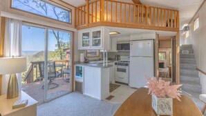 Une cuisine spacieuse avec un plafond en bois, un coin repas avec une table et une vue sur l’extérieur.
