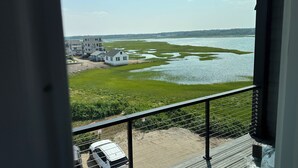 A view from a balcony overlooking a body of water with houses and a white van in the foreground. - Brand New! Enjoyable 5-bedroom house with AC in Wells Beach (Wells)
