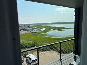 Blick von einem Balkon auf ein Gewässer mit Häusern und einem weißen Lieferwagen im Vordergrund.
