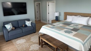 A bedroom with a bed, a sofa, a TV, a lamp, and a door. - Brand New! Enjoyable 5-bedroom house with AC in Wells Beach (Wells)