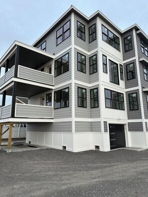 Un edificio residenziale a più piani con un balcone al piano terra, ampie finestre e un tetto piatto.