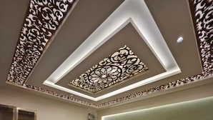 Un salon moderne avec un canapé, une table basse, un téléviseur et un plafond décoratif.