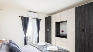 Un dormitorio moderno con una cama, un armario de madera oscura y un televisor pequeño en un estante.