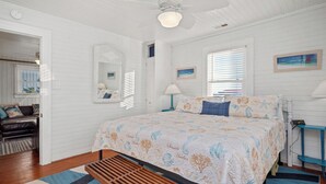 Een slaapkamer met een bed, een bankje, een spiegel en een raam met jaloezieën.