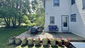 Une maison à deux étages dotée d’une terrasse, de meubles d’extérieur et de plantes en pot.