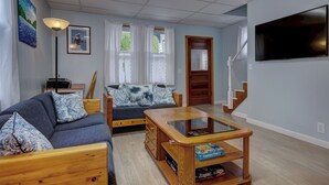 Un salon avec un canapé, une table basse, une lampe et un téléviseur.