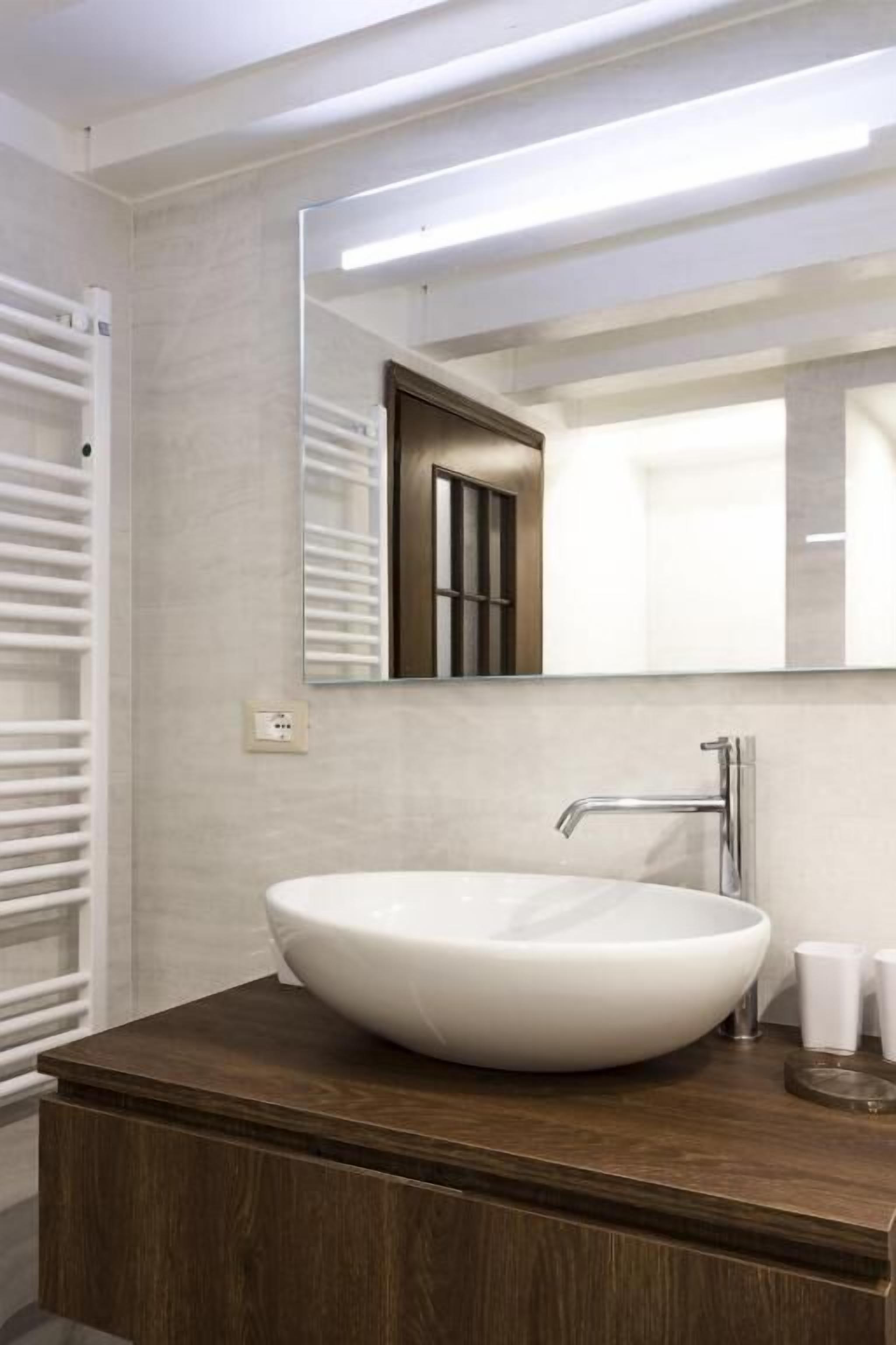 A modern bathroom with a large oval sink, a mirror, and a wooden vanity.