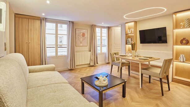 Een moderne woonkamer met een bank, eettafel, stoelen en een televisie.
