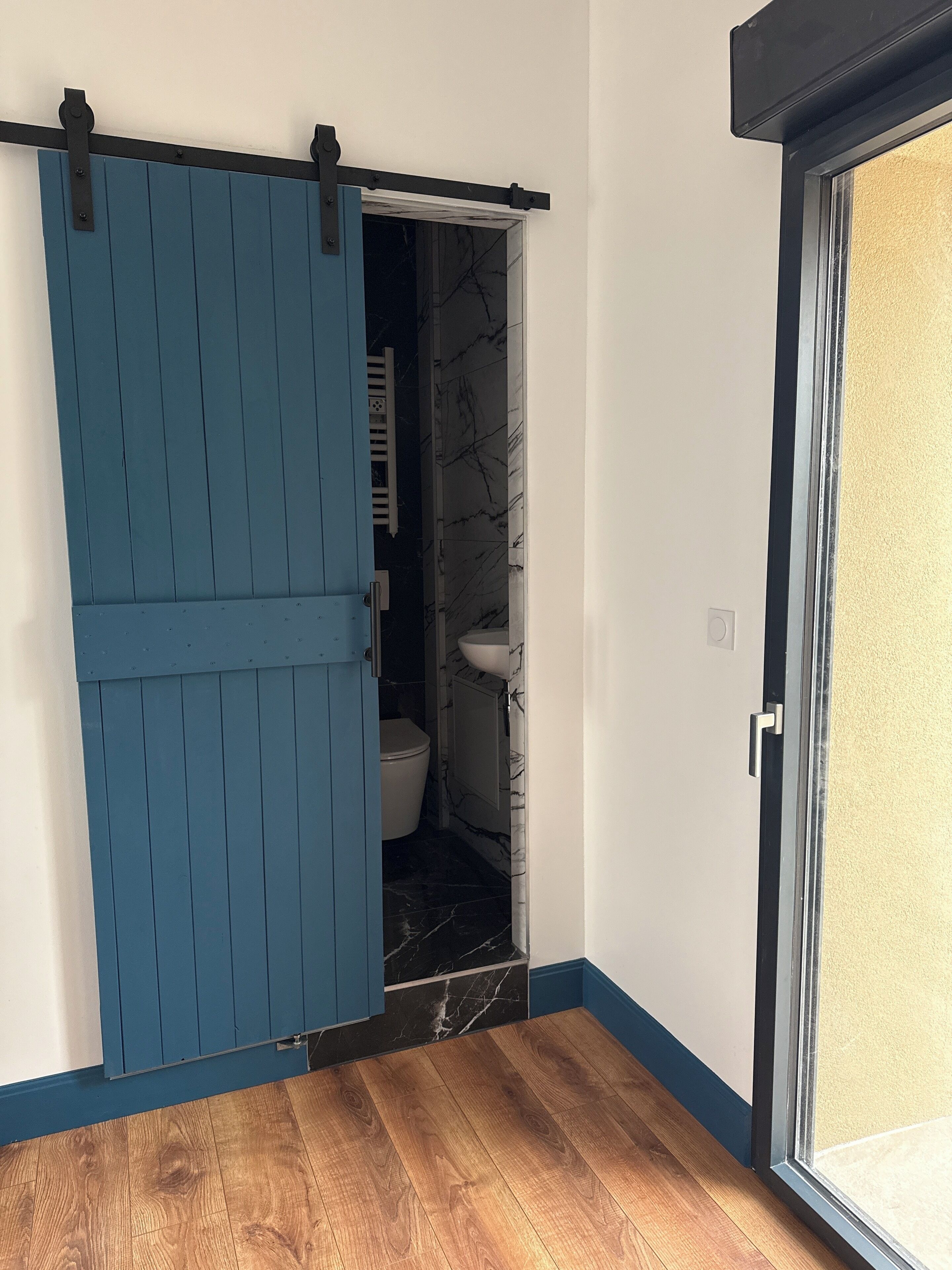 A bathroom with a toilet, sink, and blue sliding door.