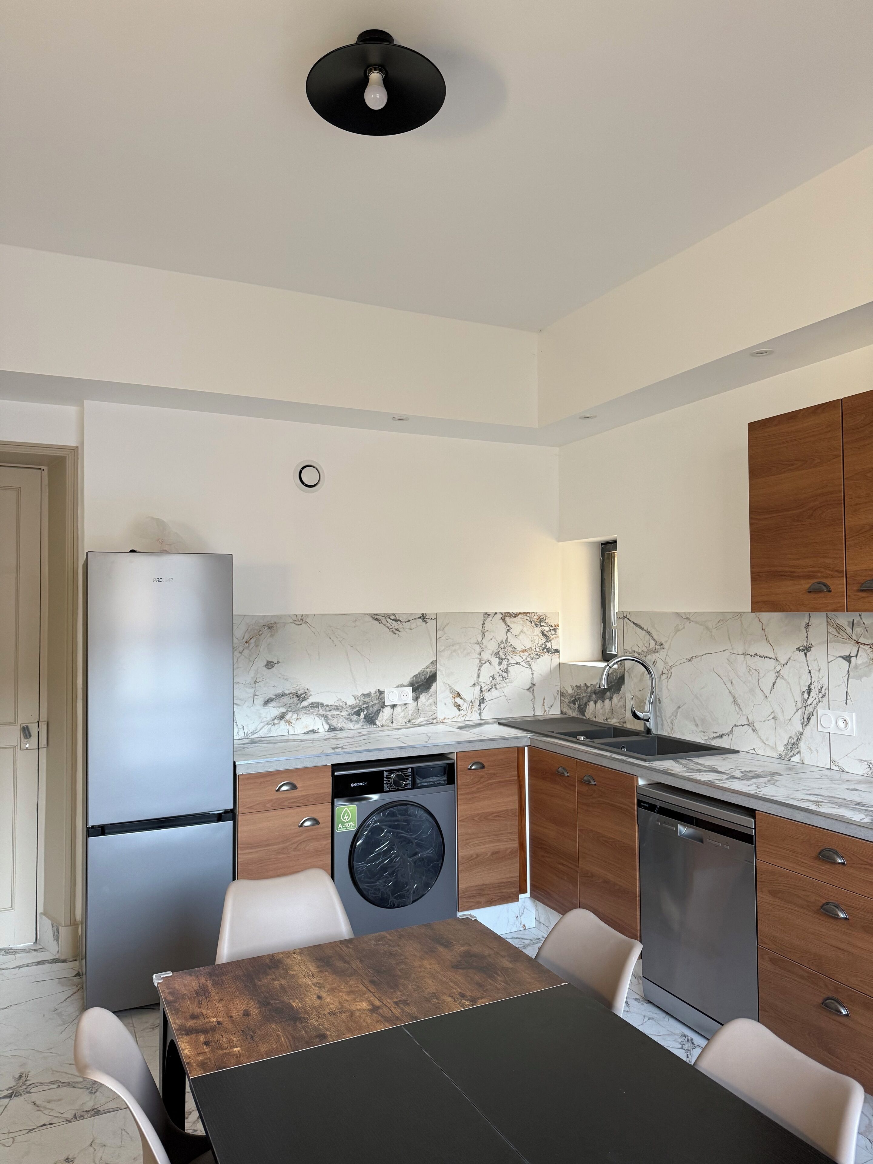 Una cucina moderna dotata di lavastoviglie, frigorifero, lavello e zona pranzo con tavolo e sedie.