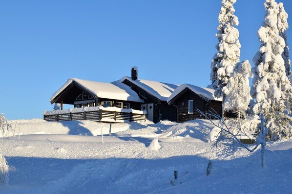 A snow-covered lodge with a wooden exterior and multiple windows, situated on a snowy hill. - Skeikampen, 7-bed cabin Fangstvegen 7 (Skeikampen)