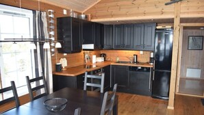 Une cuisine moderne avec des meubles en bois, un réfrigérateur noir et une table à manger avec des chaises.