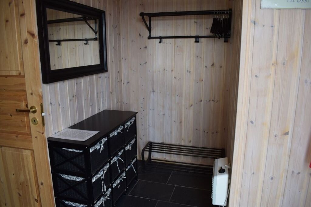 Ein kleines, kompaktes Badezimmer mit einer Holzverkleidung, einer schwarzen Arbeitsplatte und einem Metallregal.