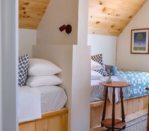 Ein Zimmer mit einem Etagenbett, einem kleinen Tisch und einem gerahmten Bild an der Wand.