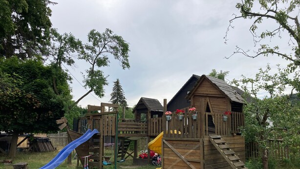 A wooden play structure with a blue slide and a yellow climbing area. - Holiday Apartment by the Zschopau River (Niederwiesa)