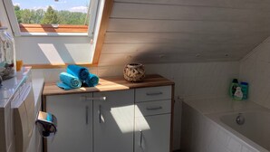A skylight, a wooden cabinet, a bathtub, and a small window. - Holiday Apartment by the Zschopau River (Niederwiesa)
