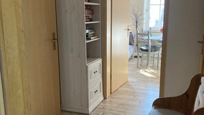 A hallway with a wooden wardrobe, a white cabinet, and a wooden bench. - Holiday Apartment by the Zschopau River (Niederwiesa)