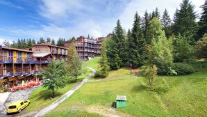 Ein mehrstöckiges Hotel mit Außenbestuhlung und einem Weg zu einem Parkplatz.