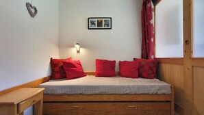 Ein kleines, gemütliches Zimmer mit einem Einzelbett, einem Nachttisch, einer Wandleuchte und einem gerahmten Bild.