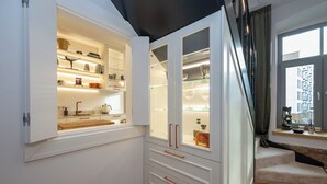 Une cuisine moderne avec des meubles blancs, un plan de travail en bois et un four encastré.