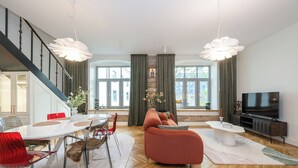 Un salon moderne comprenant un coin repas, un canapé, un téléviseur et un escalier.