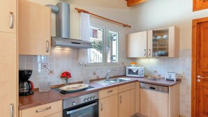A kitchen with wooden cabinets, a stainless steel range hood, a built-in microwave, and a dishwasher. - Villa Avgerini Paxos I: Deluxe beachfront apartment with breathtaking sea views (Gaios)