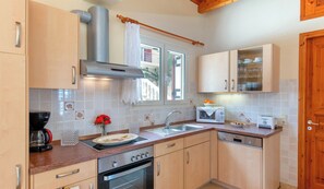 A kitchen with wooden cabinets, a stainless steel range hood, a built-in microwave, and a dishwasher. - Villa Avgerini Paxos I: Deluxe beachfront apartment with breathtaking sea views (Gaios)