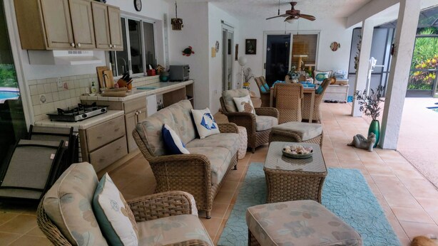 A spacious living area with wicker furniture, a kitchen with a gas stove, and a dining area with a table and chairs. - Tropical paradise getaway on the Treasure Coast -FL- (Jensen Beach)