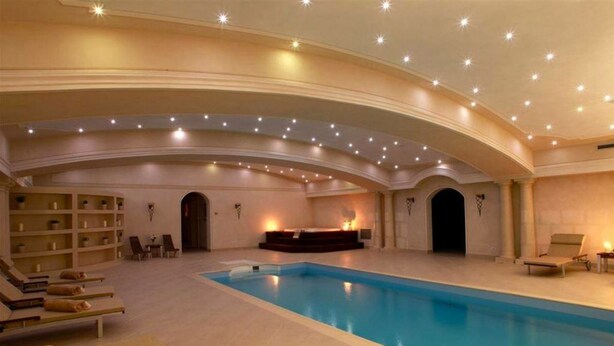 Un'ampia piscina coperta con lettini e una zona centrale con camino.